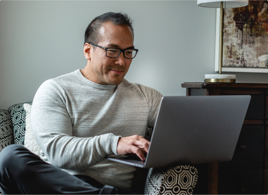 Person sitting in armchair with laptop.